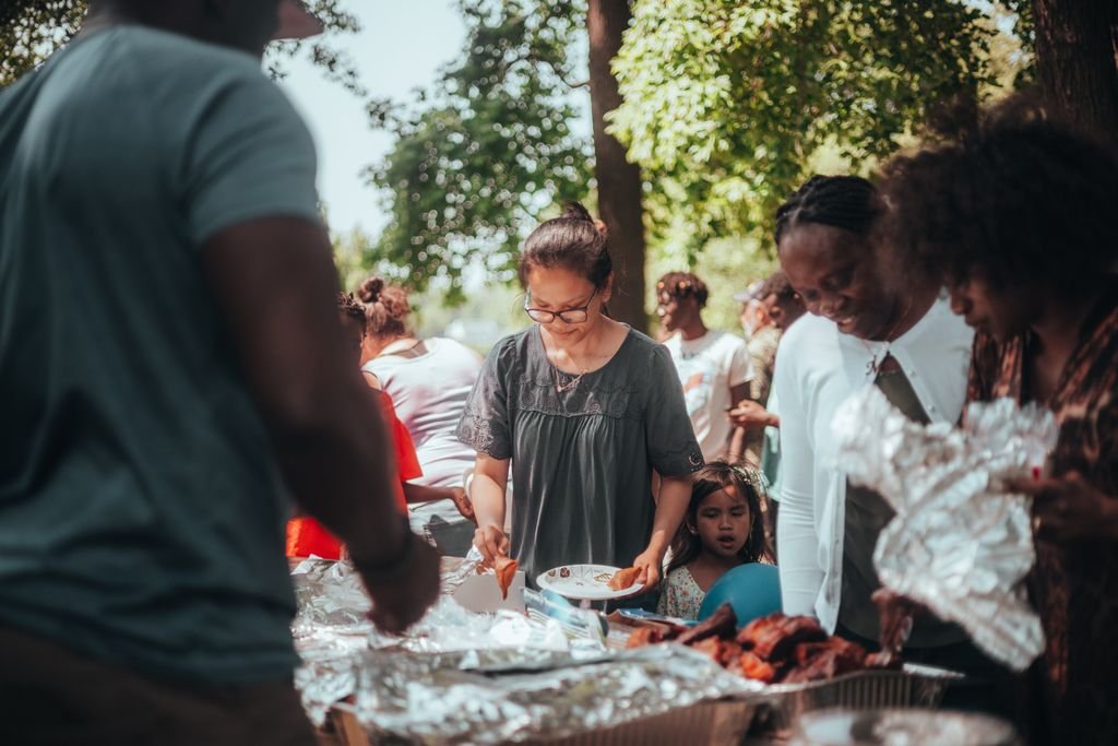 A lively barbecue gathering with diverse group outdoors enjoying food and summer weather.